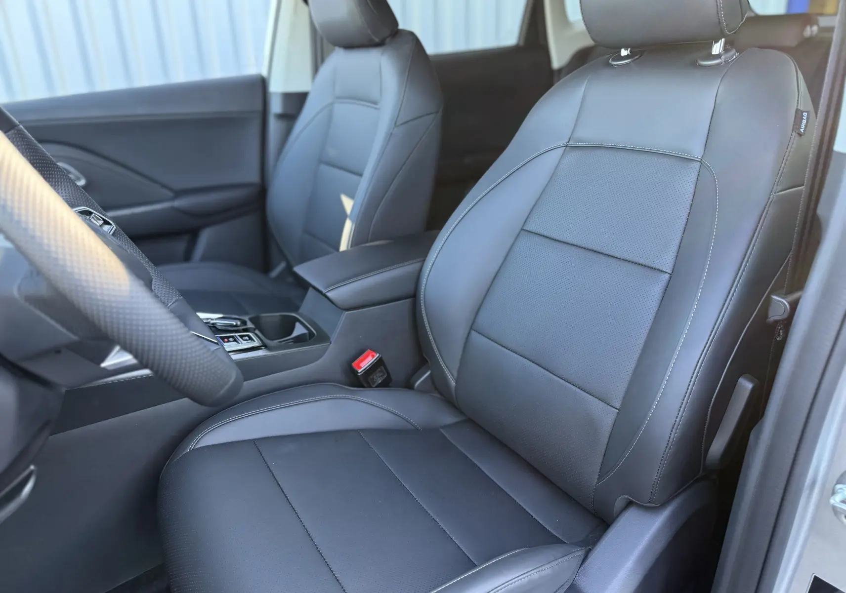 Vue intérieure côté conducteur du MG ZS 1.5 L Hybrid+ 2026 avec sièges en cuir noir et console centrale visible.