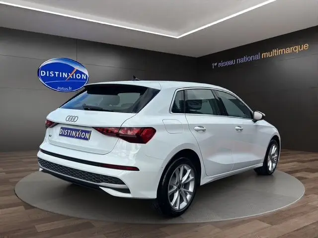 Audi A3 Sportback blanc Arkona vue 3/4 arrière droit en intérieur avec jantes alliage léger et feux LED distinctifs.