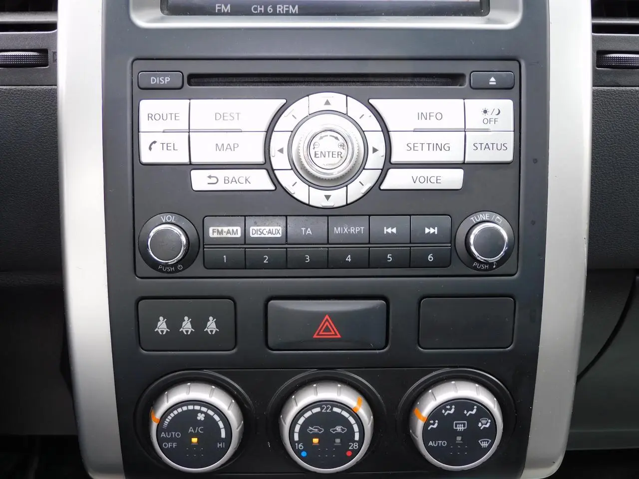 Gros plan sur la console centrale du Nissan X-TRAIL noir 2011, mettant en valeur les commandes audio et climatisation.
