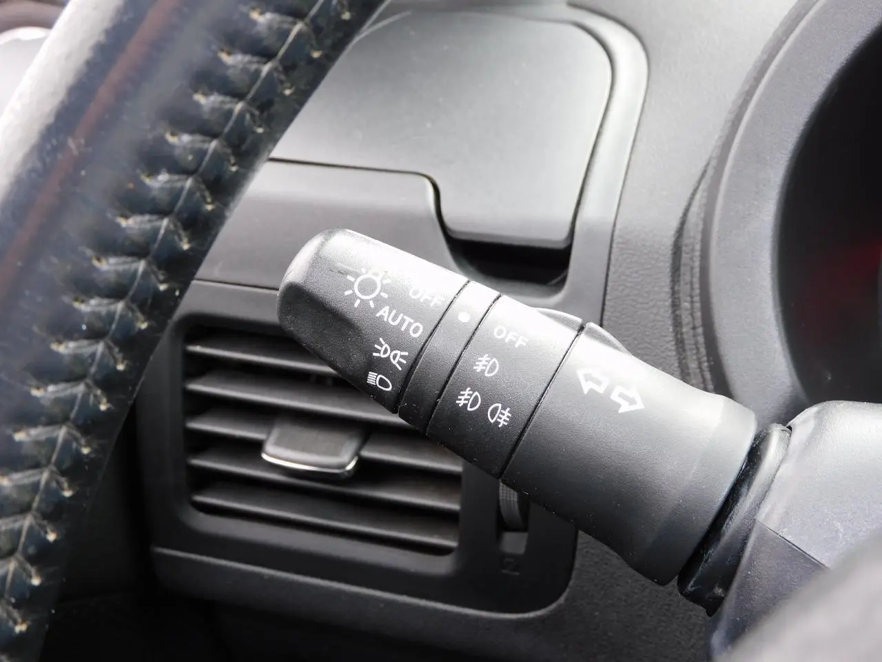 Gros plan sur la commande des phares et clignotants du Nissan X-TRAIL noir, intérieur côté conducteur.