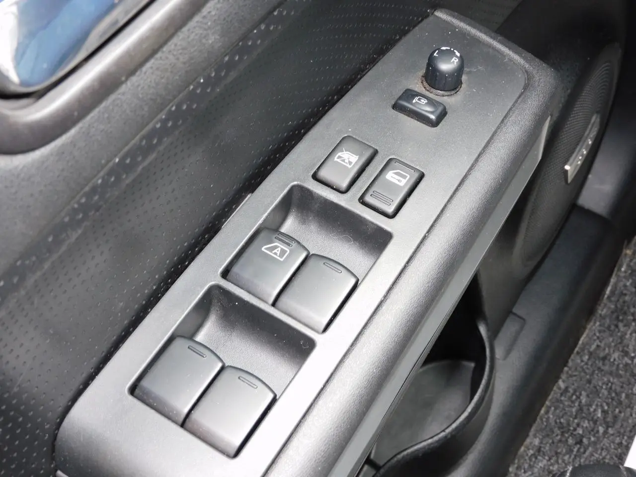 Gros plan sur la commande des vitres côté conducteur du Nissan X-TRAIL noir, avec haut-parleur Bose intégré visible.