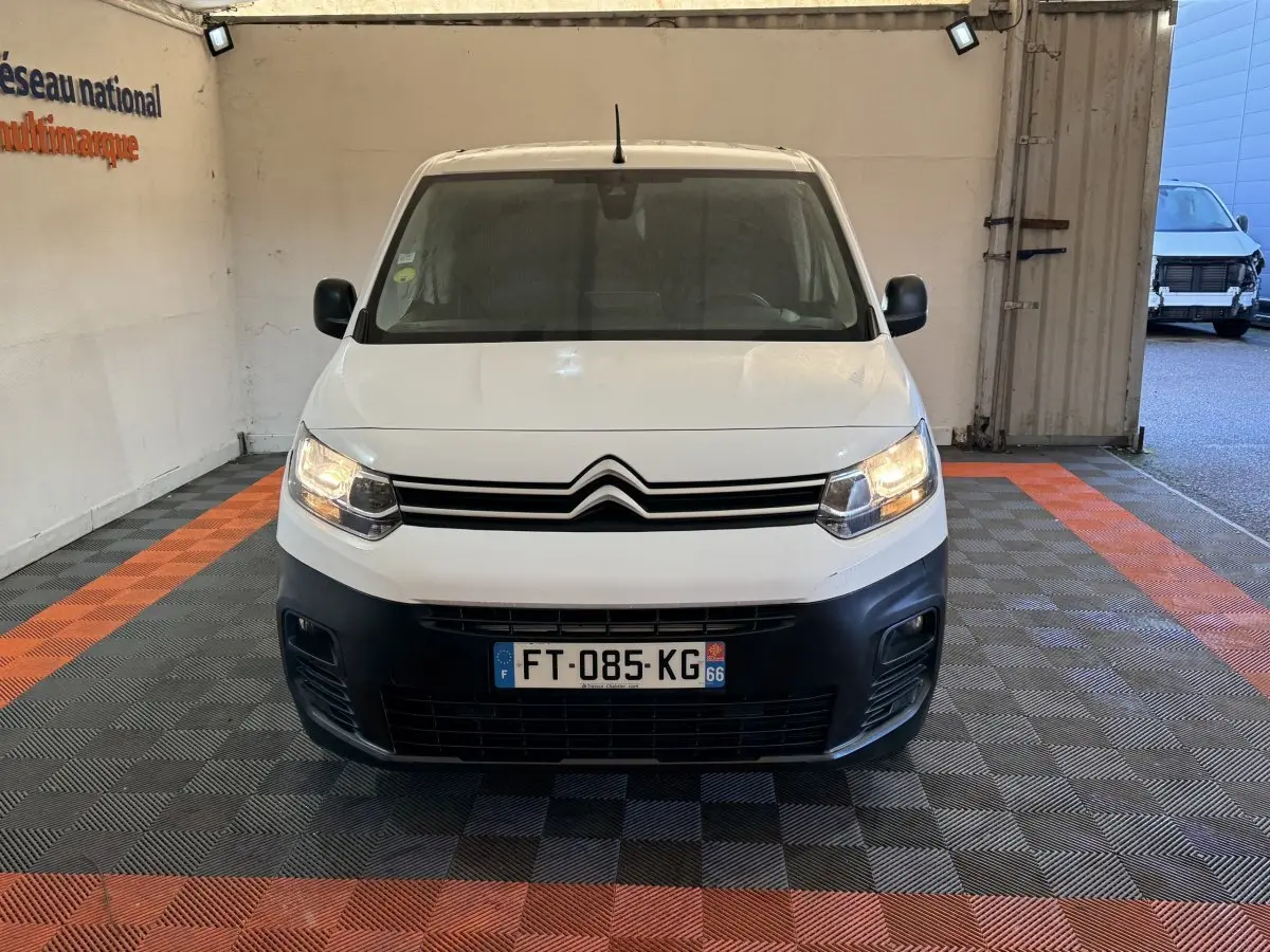 Vue de face du Citroën Berlingo blanc 2020 avec phares allumés et pare-chocs noir dans un garage.