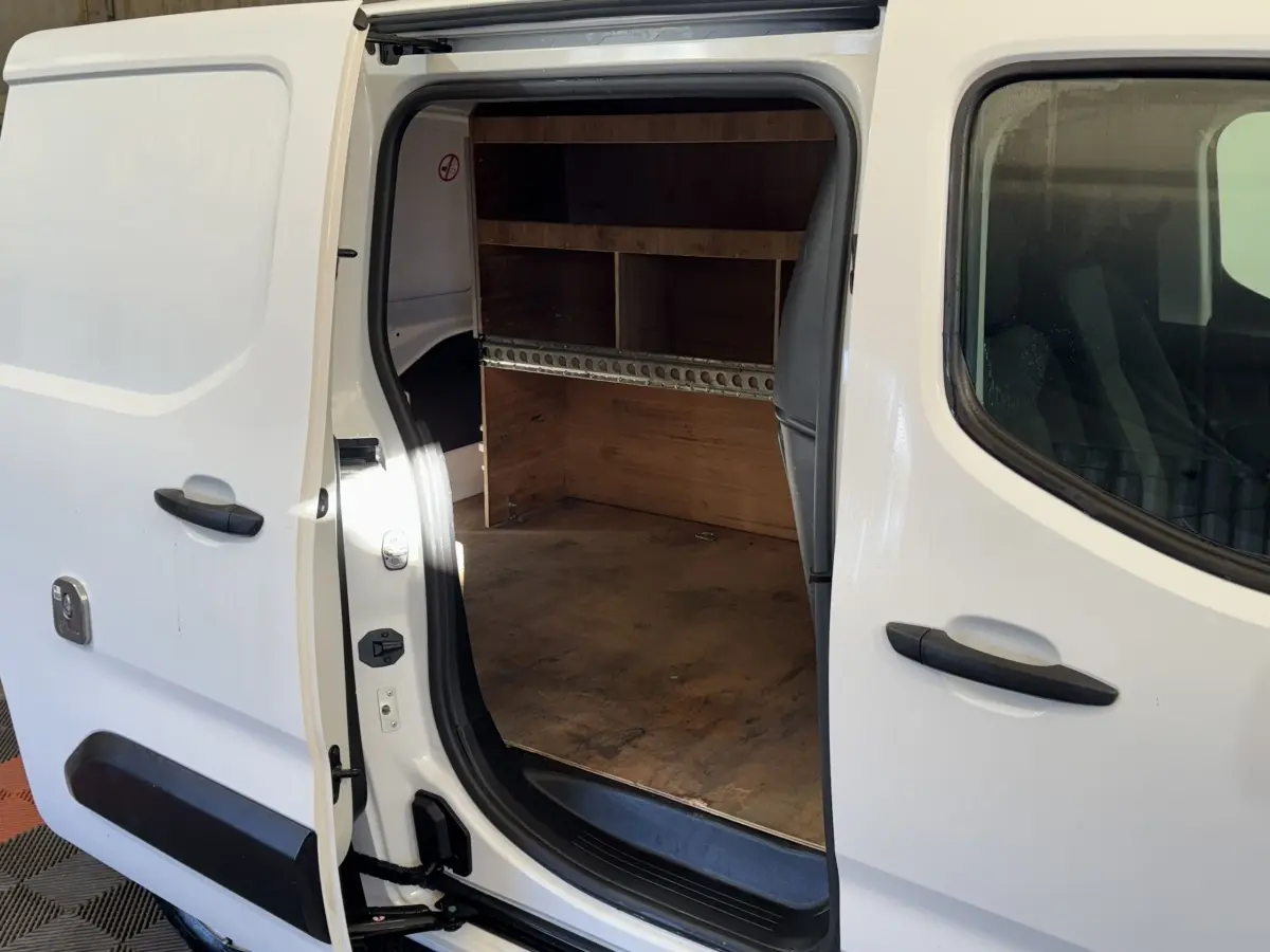 Vue latérale droite d’un Citroën Berlingo blanc 2020 avec porte coulissante ouverte montrant l’espace de chargement en bois.