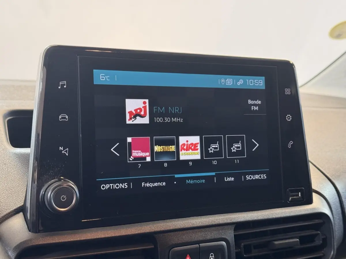 Écran tactile central du tableau de bord du Citroën Berlingo blanc, affichant les stations radio FM.