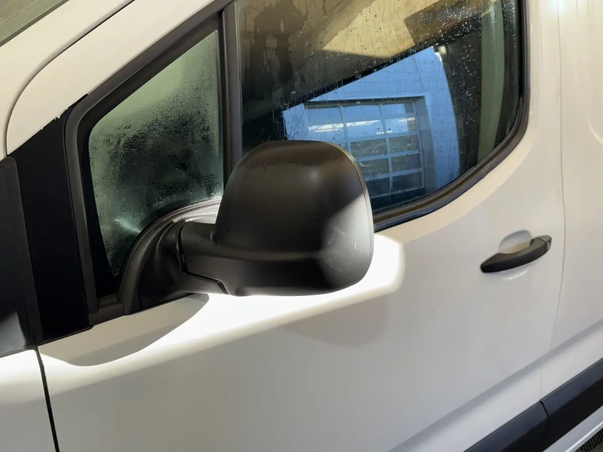 Rétroviseur noir côté conducteur en gros plan sur la porte blanche d'un Citroën Berlingo 2020.