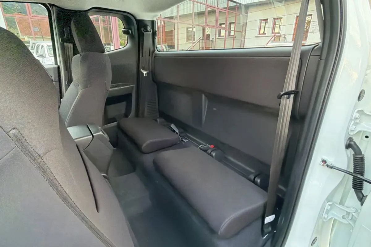 Vue intérieure côté droit du pick-up Isuzu D-MAX 2.2 TD Splash white, montrant les sièges arrière rabattus en tissu noir.