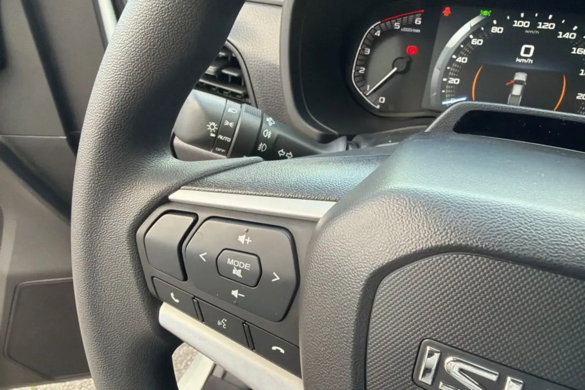 Gros plan sur le volant multifonctions noir de l'Isuzu D-MAX 2026 avec commandes audio et tableau de bord numérique.