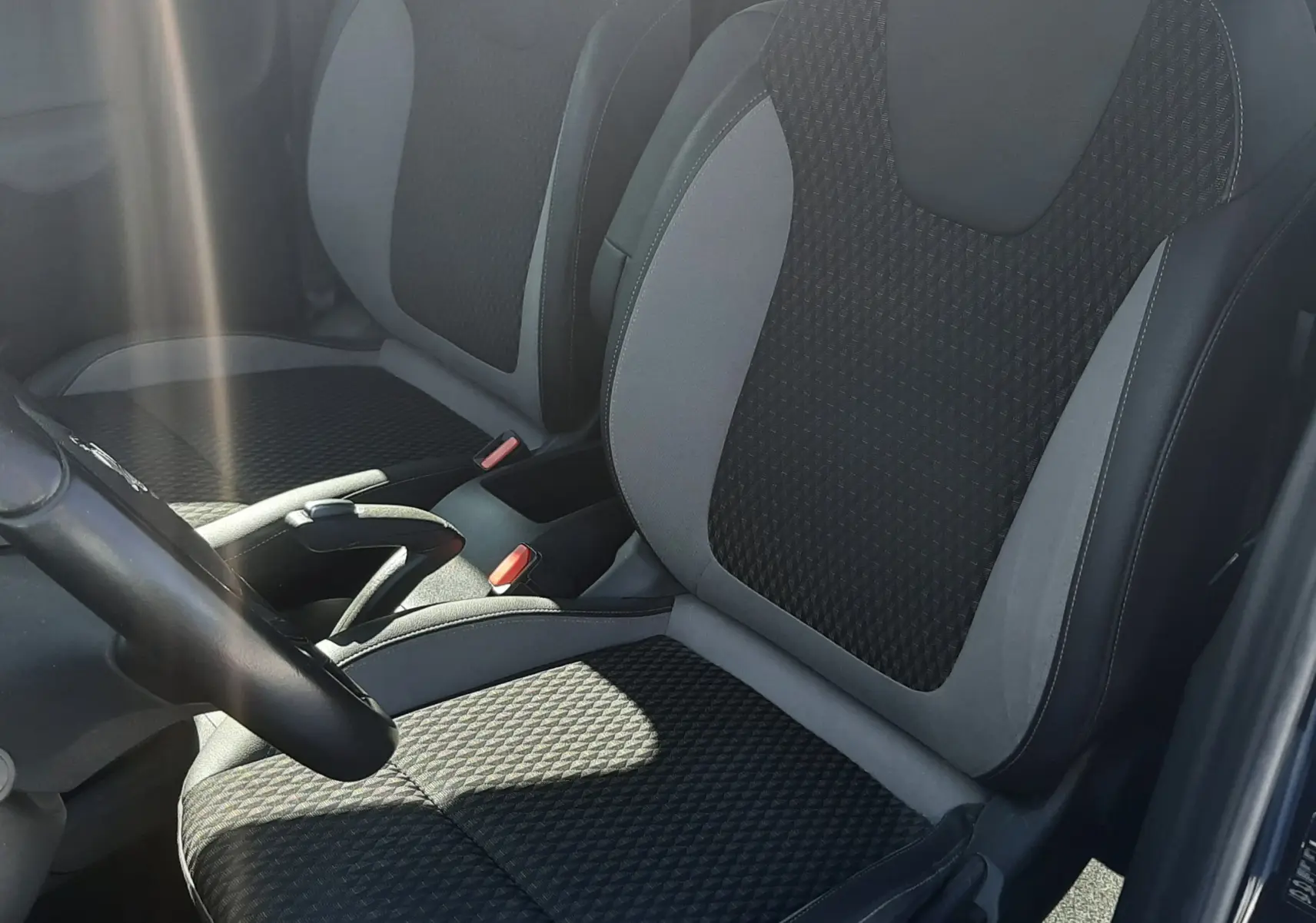 Intérieur avant droit de l’Opel Crossland noir, sièges tissu gris foncé avec console centrale et volant visibles.