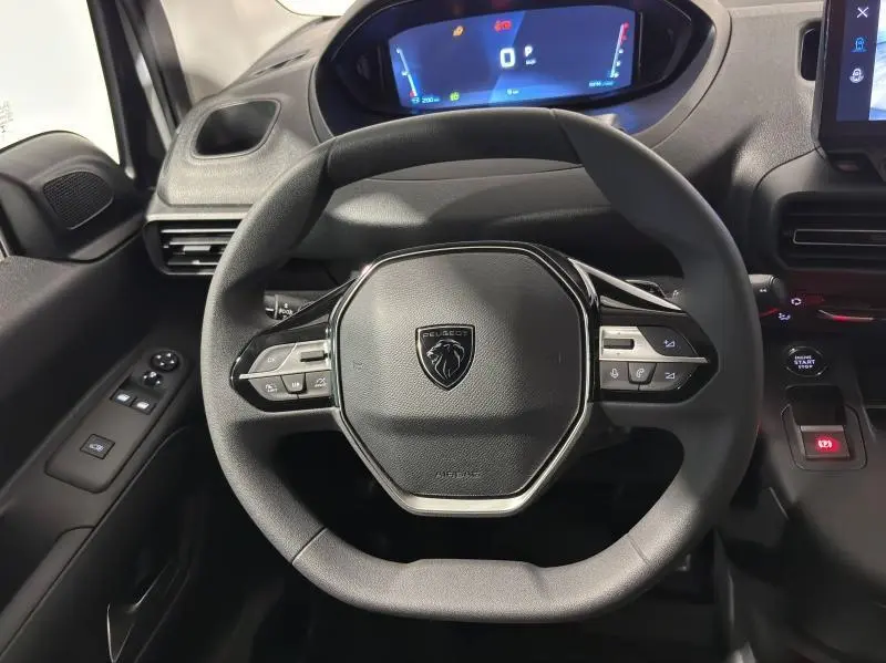 Vue rapprochée du volant multifonction noir du Peugeot Partner XL 2025 avec tableau de bord digital lumineux.
