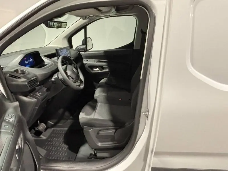 Vue intérieure côté conducteur du Peugeot Partner XL blanc Icy, montrant le tableau de bord et les sièges noirs.