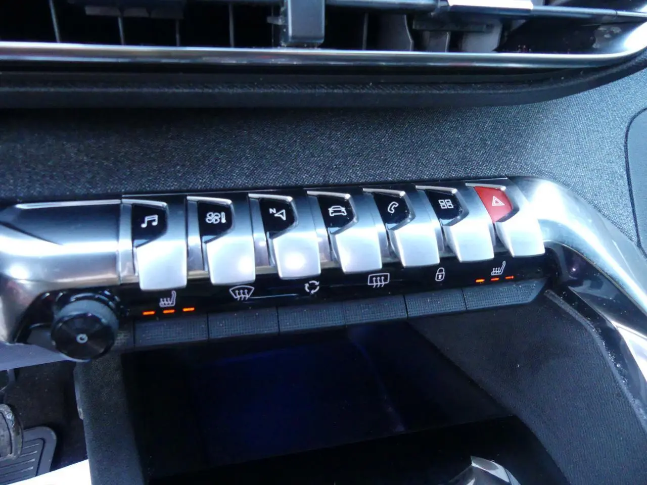 Boutons de commande chromés du tableau de bord du Peugeot 3008 GT Line 2020, avec éclairage orange des sièges chauffants.