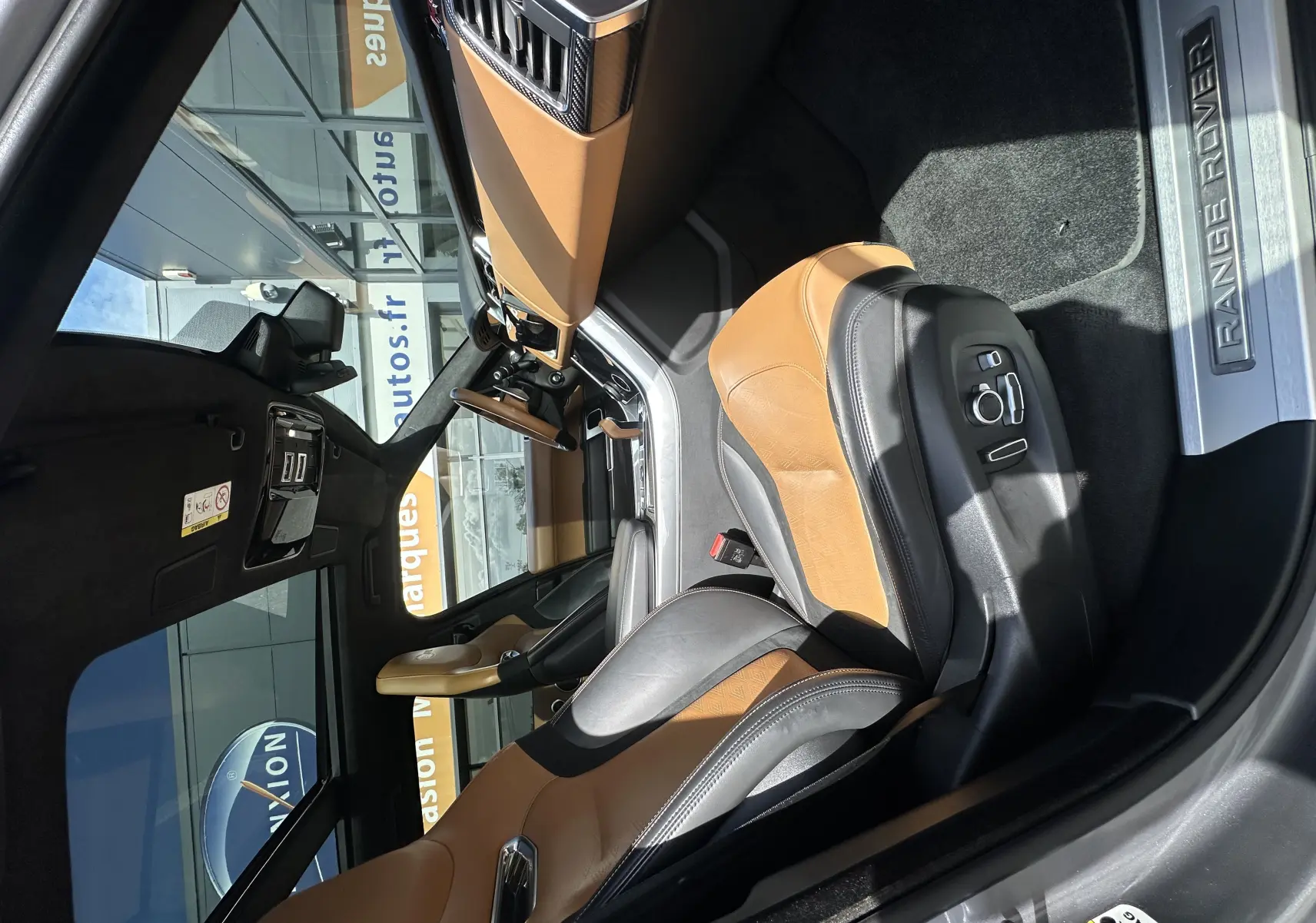 Intérieur du Range Rover Sport 2020 vu côté conducteur, sièges cuir bicolore camel et noir avec seuil "Range Rover" en acier.