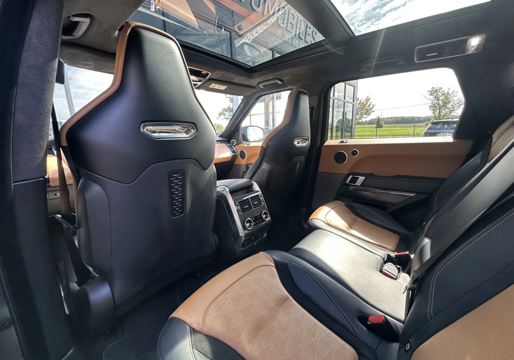 Vue intérieure arrière du Range Rover Sport SVR 2020 avec sièges cuir bicolores camel et noir et toit panoramique.