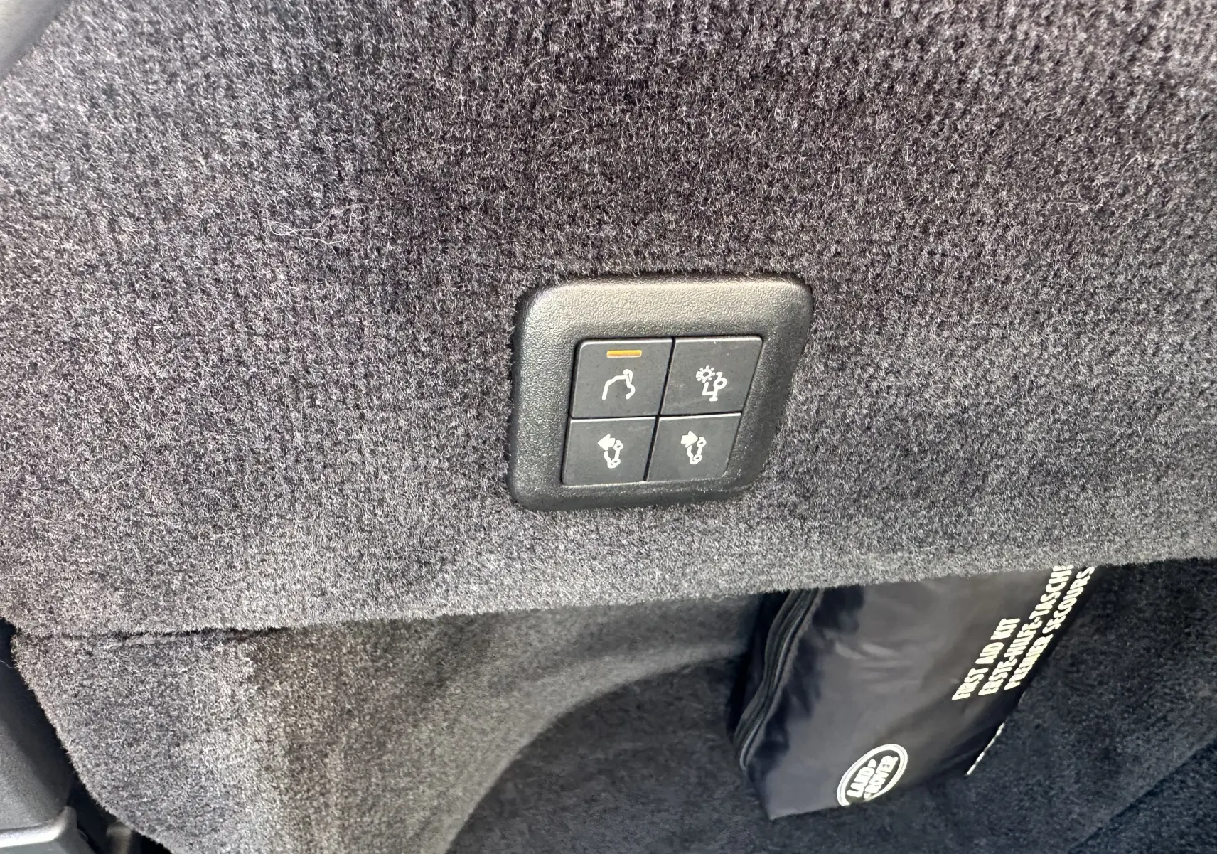 Boutons de commande du hayon électrique sur revêtement gris foncé dans le coffre d'un Range Rover Sport II V8 5.0 Supercharged SVR Carbon Edition 2020.