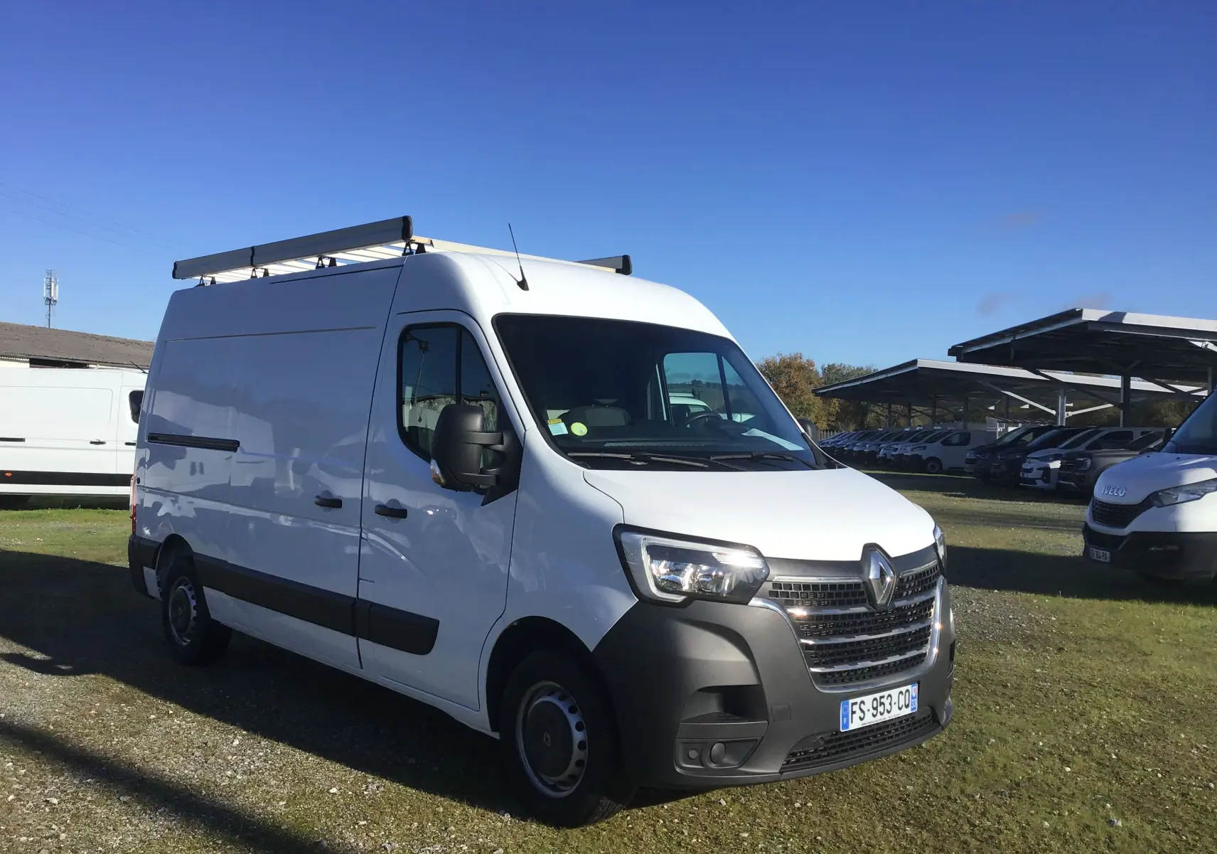 Renault Master blanc en vue 3/4 avant droit, fourgon utilitaire avec galerie de toit et rétroviseurs noirs.