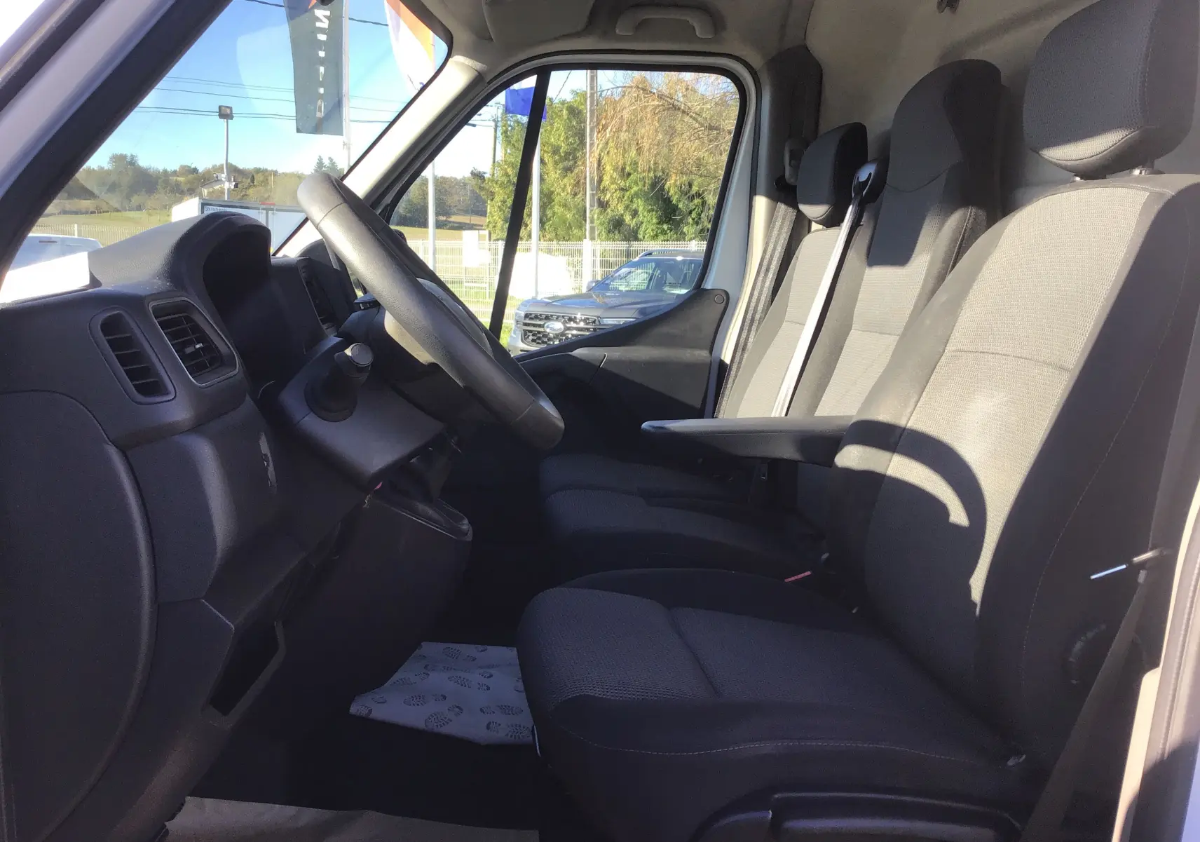 Vue intérieure côté conducteur du Renault Master 2020, sièges tissu noir et gris avec accoudoir central.