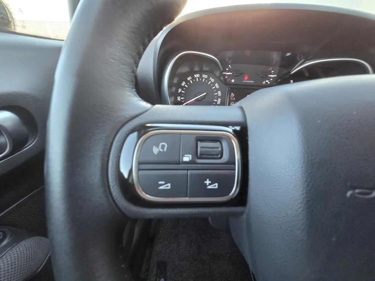 Gros plan sur les commandes audio au volant cuir noir du Citroën C3 Aircross 2021, tableau de bord en arrière-plan.