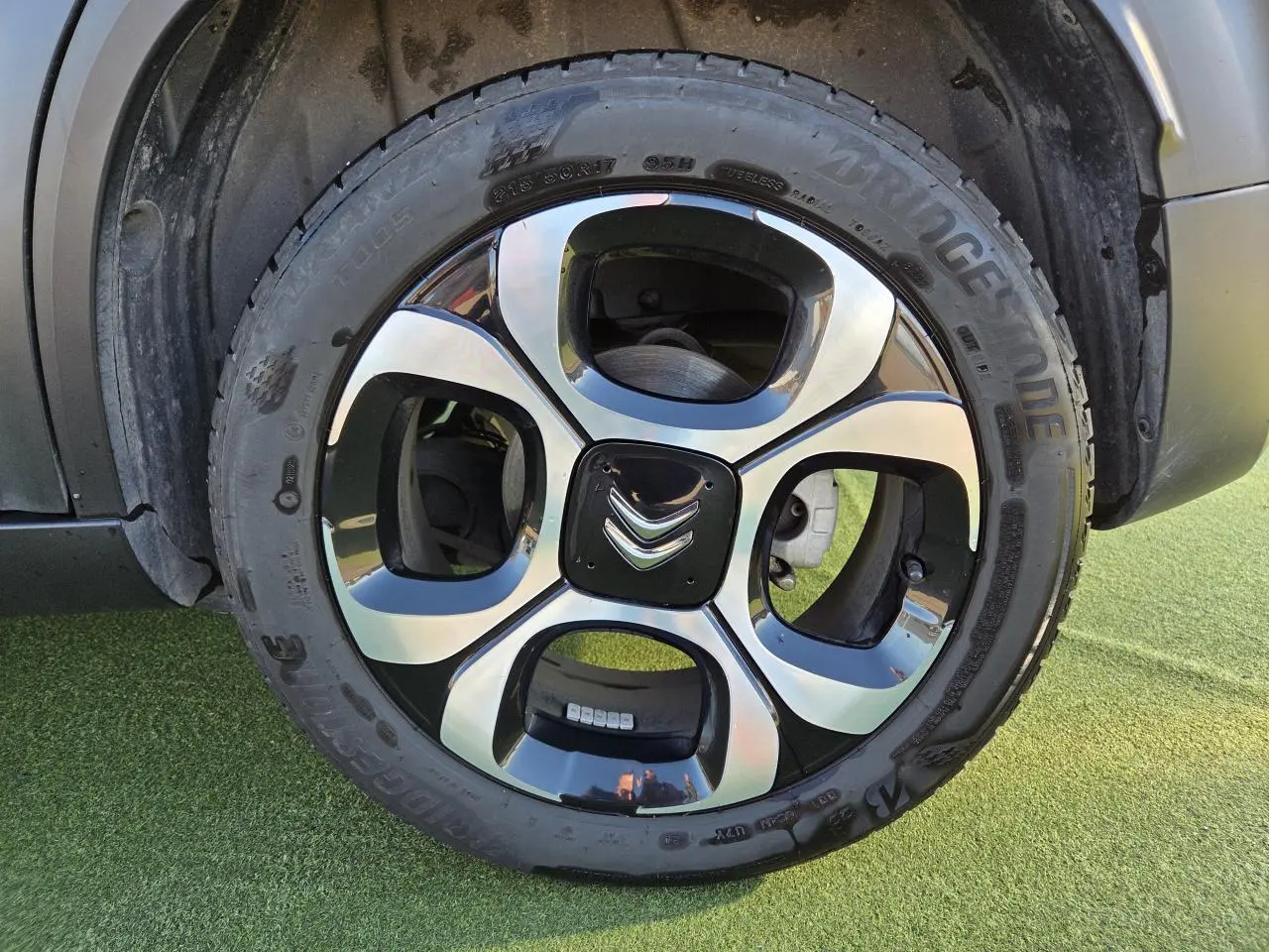 Gros plan sur la roue arrière droite d'une Citroën C3 Aircross gris platinium avec jante alliage 17'' damantée.