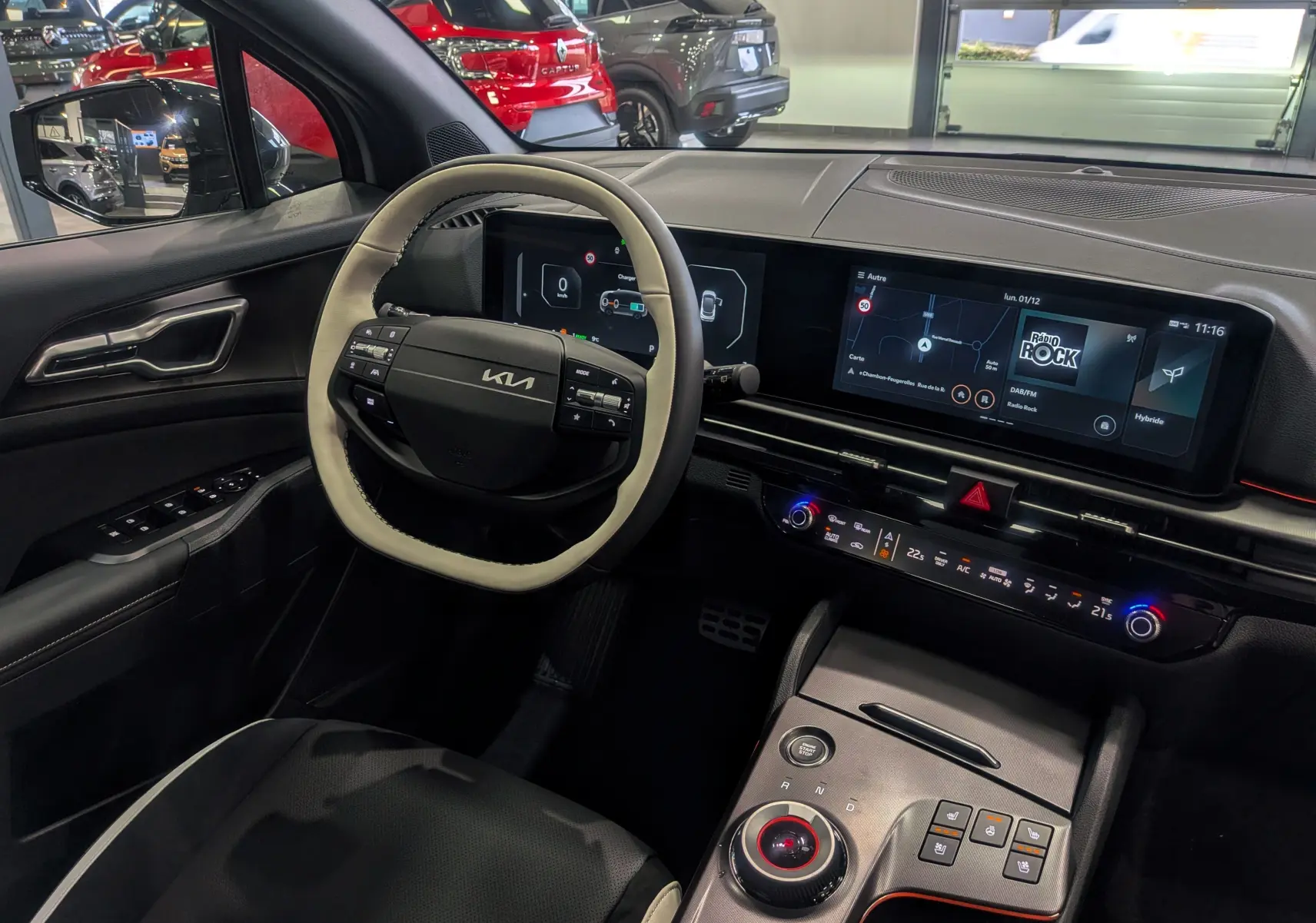 Vue intérieure côté conducteur du Kia Sportage 2025 hybride, volant cuir clair et tableau de bord numérique moderne.