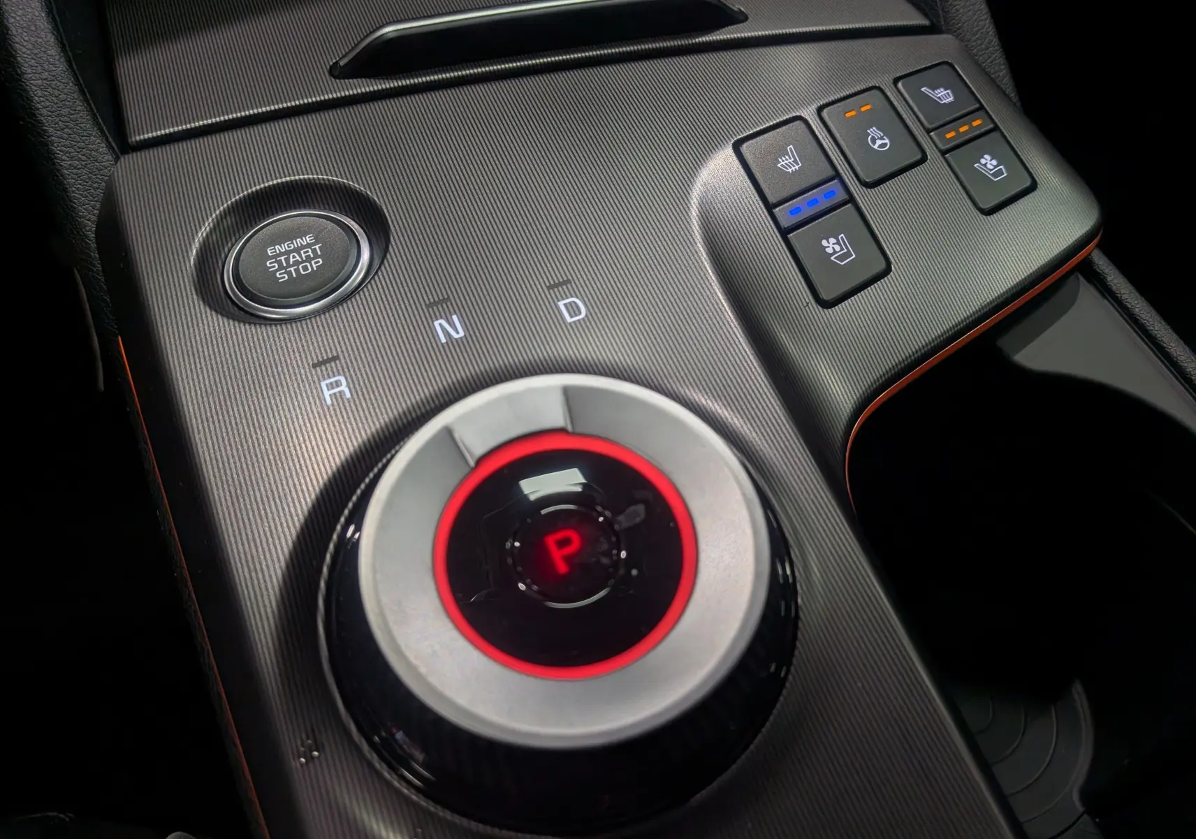 Gros plan sur la console centrale du Kia Sportage 2025 avec sélecteur rotatif de boîte auto et commandes de sièges chauffants.