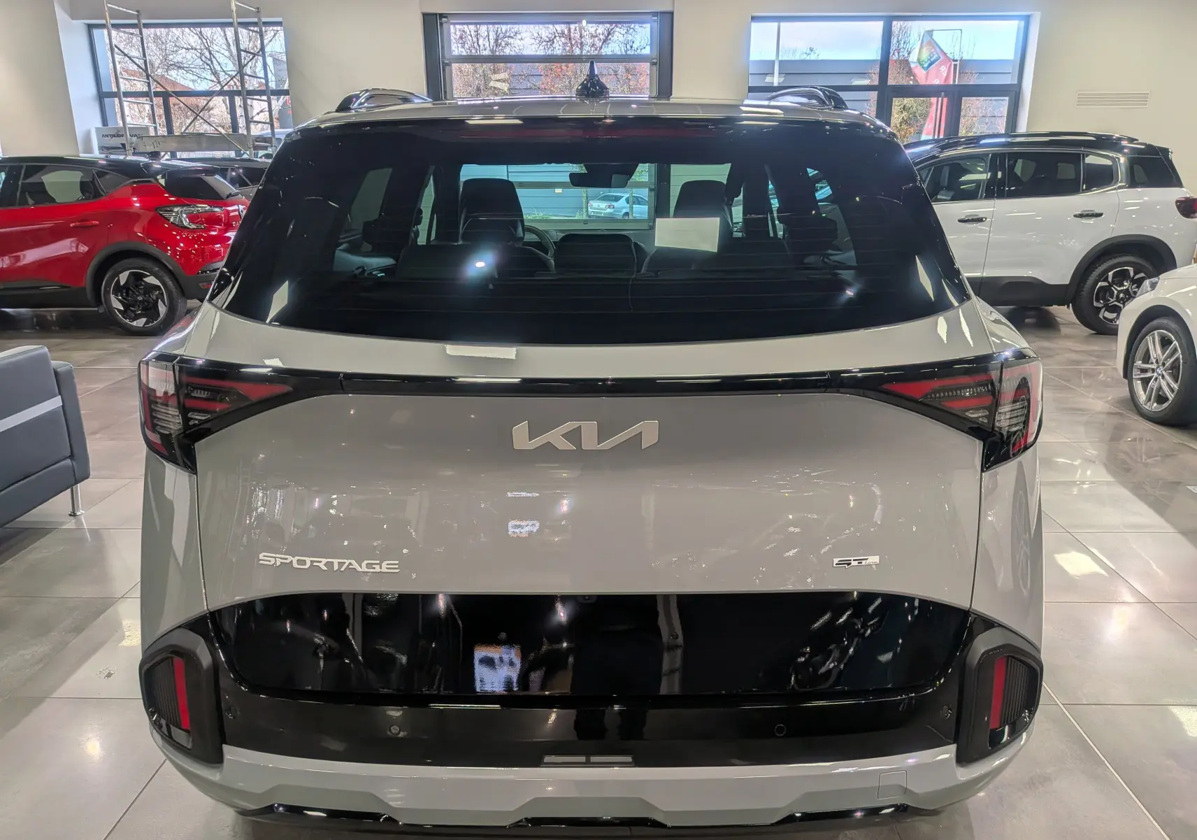Vue arrière du Kia Sportage 2025 gris céramique avec toit noir et détails noirs brillants sur le hayon et les feux.