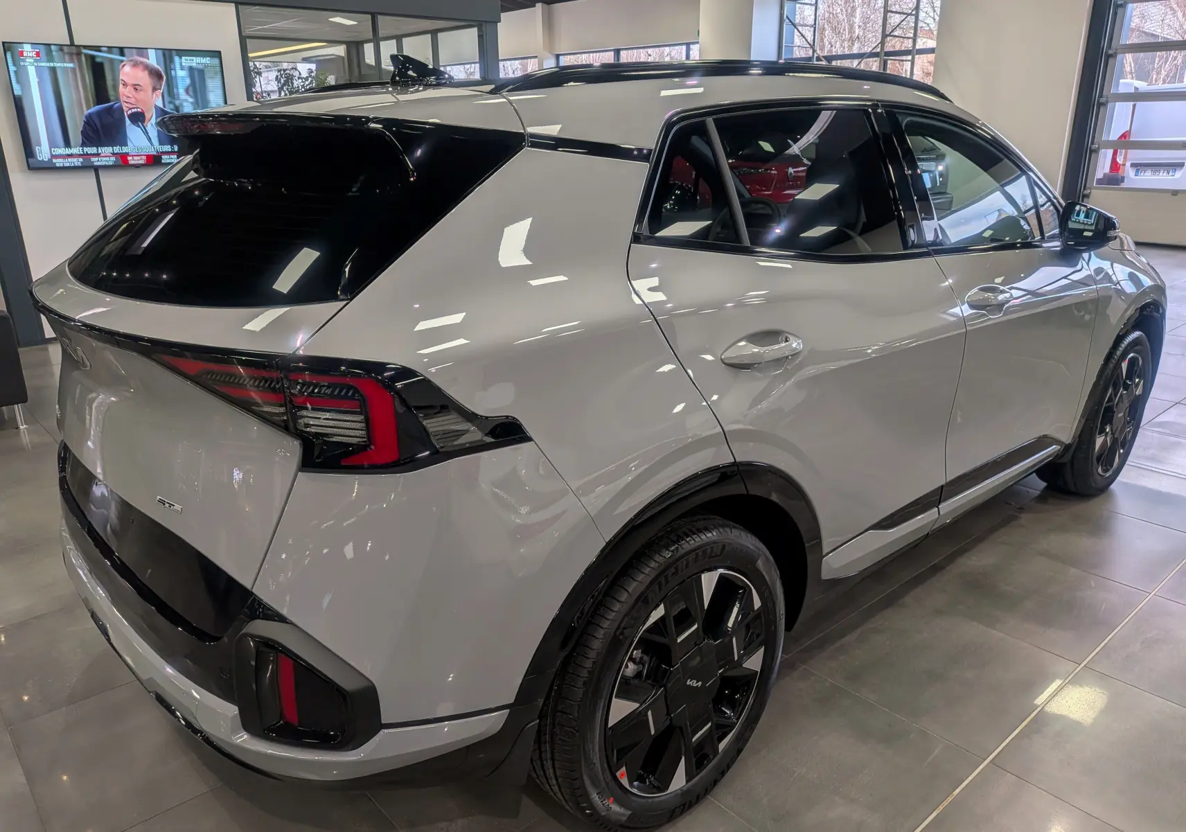 Vue 3/4 arrière droite du KIA Sportage 2025 gris céramique avec toit noir et jantes noires distinctives.