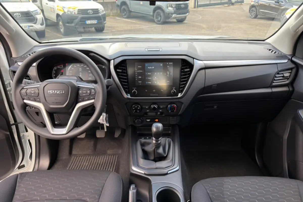 Intérieur de l'Isuzu D-MAX 2026 vue de face, tableau de bord noir avec écran tactile et boîte manuelle.