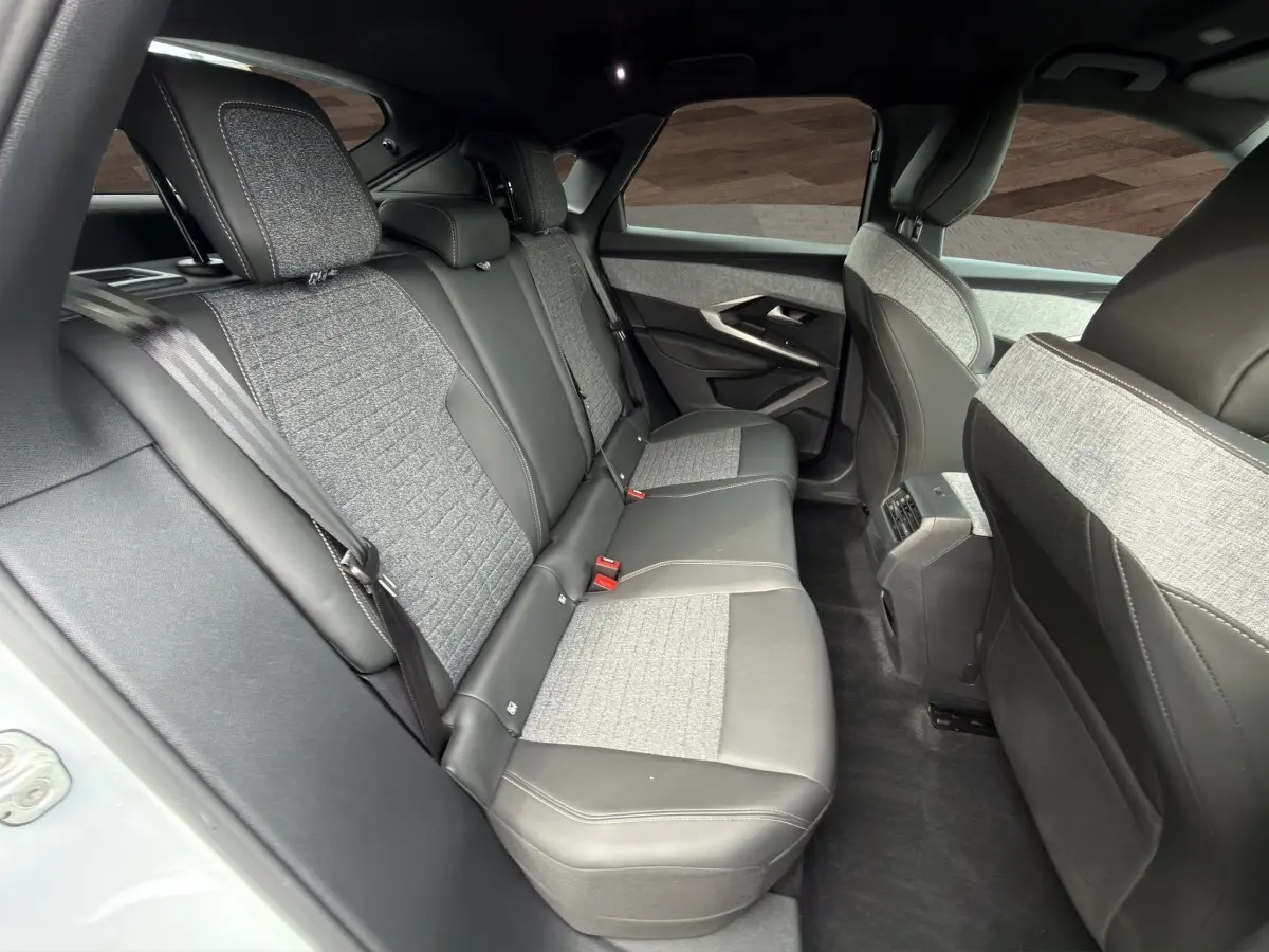 Vue intérieure arrière du Peugeot 3008 2025, sièges bi-matière gris clair et cuir noir avec ceinture de sécurité visible.