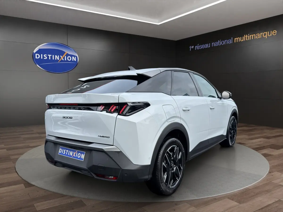 Vue 3/4 arrière droite du Peugeot 3008 blanc hybride avec feux arrière LED et jantes noires distinctives.
