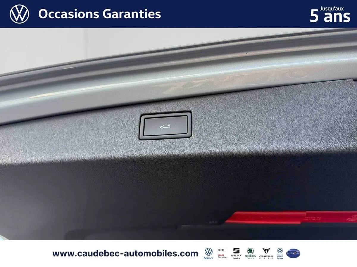 Détail du bouton d'ouverture électrique du hayon sur un Volkswagen Tiguan argent Dolomite, vue intérieure du coffre.