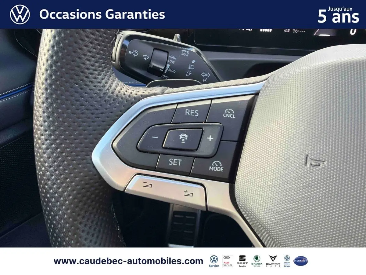 Gros plan sur le volant cuir perforé du Volkswagen Tiguan eHybrid 2025 avec commandes multifonctions et finition argentée.