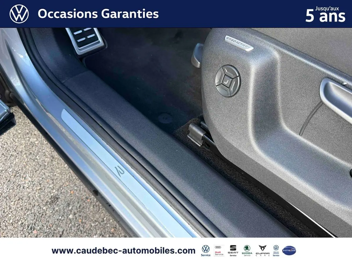 Détail de la porte côté conducteur du Volkswagen Tiguan eHybrid argent Dolomite avec seuil de porte ErgoActive visible.