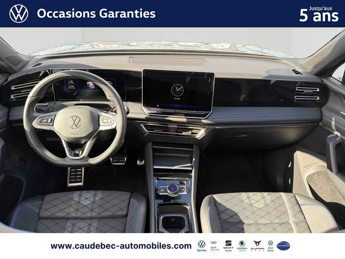 Vue intérieure avant du Volkswagen Tiguan 2025, tableau de bord noir avec écran tactile central et volant multifonction.