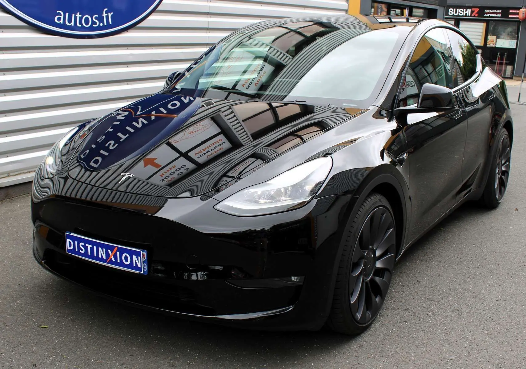 Tesla Model Y Performance noir métal vue 3/4 avant droit, roues noires et surface brillante réfléchissante.