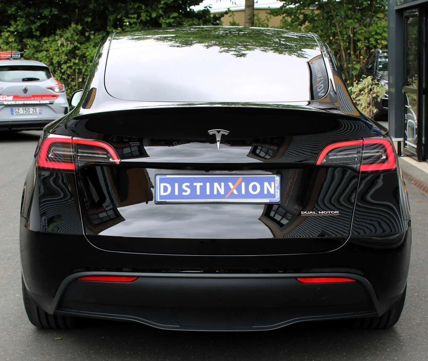 Vue arrière d'une Tesla Model Y noire métal 2024 avec logo "Dual Motor" et plaque Distinxion visible.