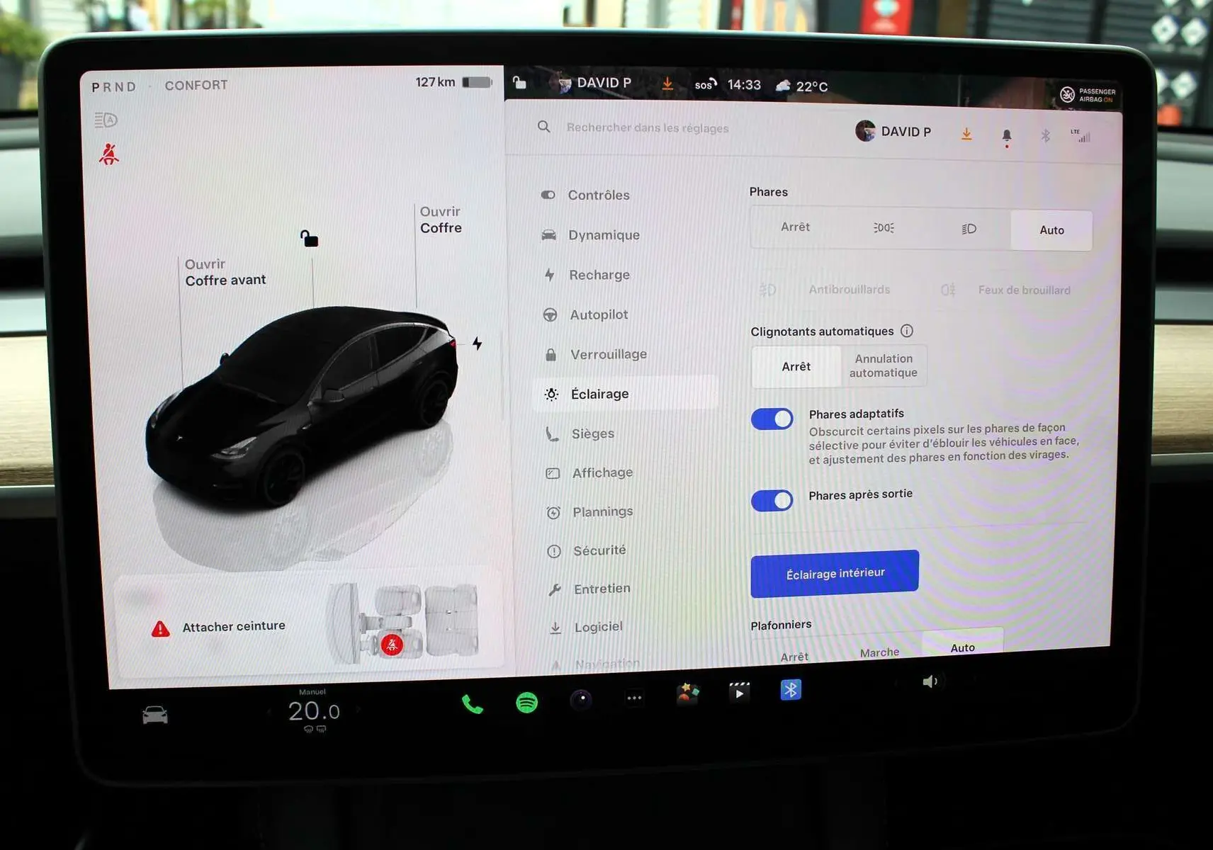 Écran tactile central d'une Tesla Model Y noir métal 2024 montrant les réglages d'éclairage et l'interface du véhicule.