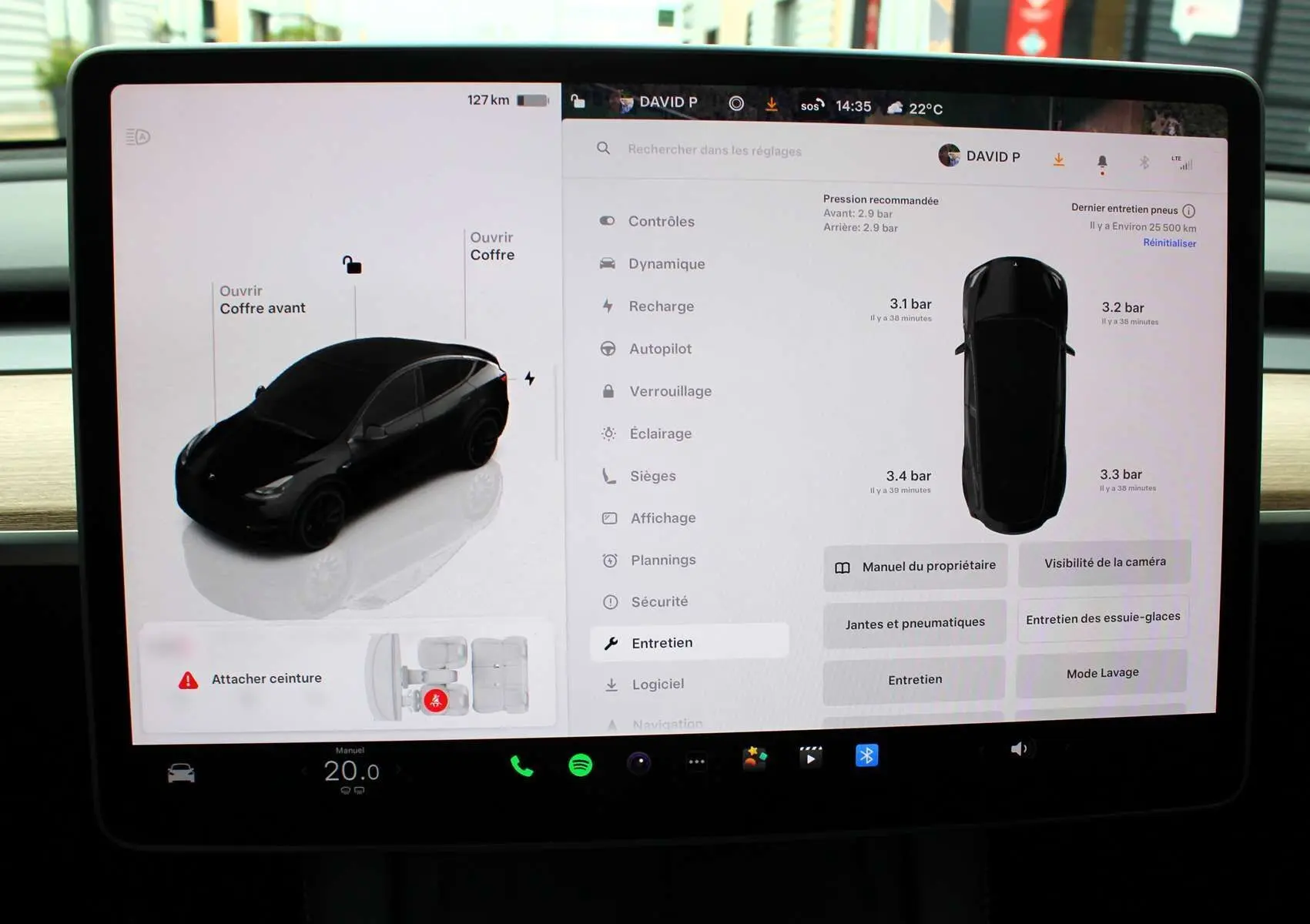 Écran tactile du tableau de bord d'une Tesla Model Y noire métal 2024 montrant l'état des pneus et options d'entretien.