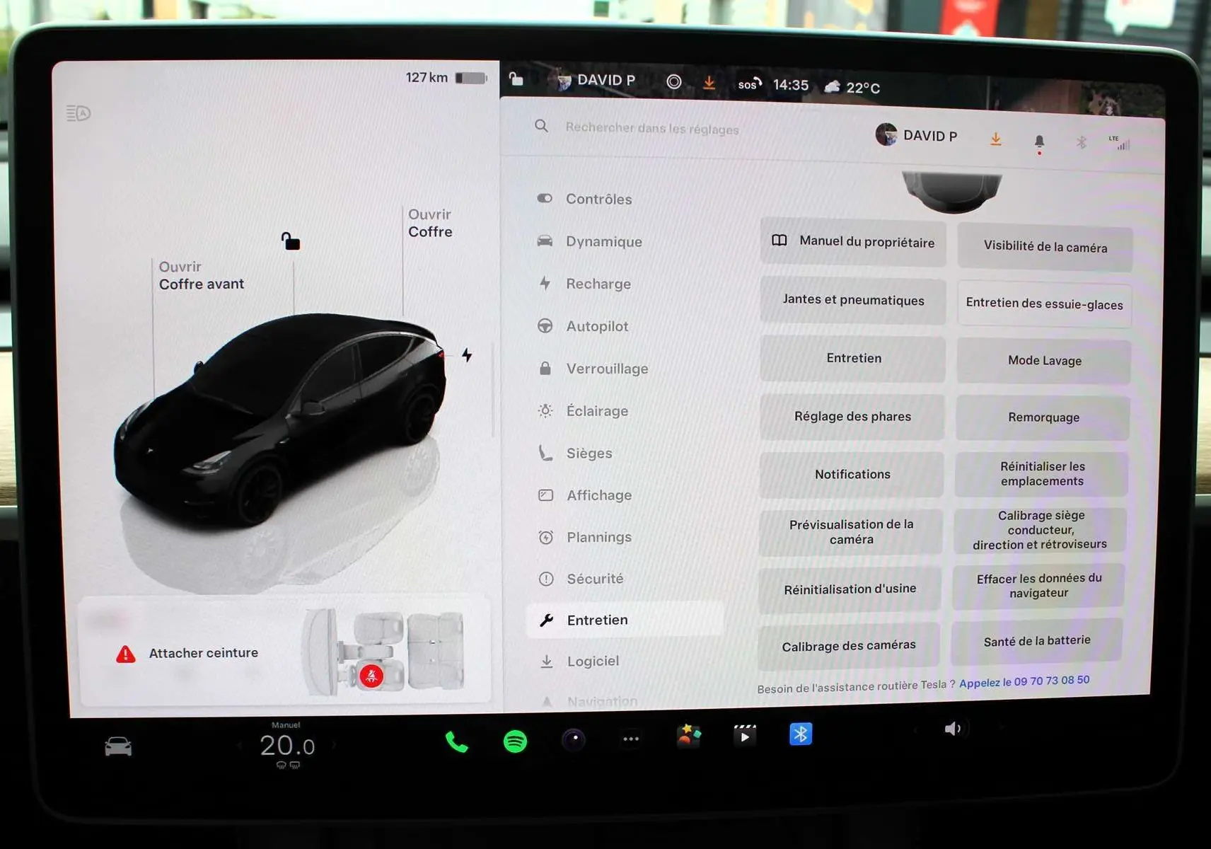 Écran tactile central de la Tesla Model Y 2024 noir métal montrant le menu d'entretien et l'état du véhicule en vue de dessus.