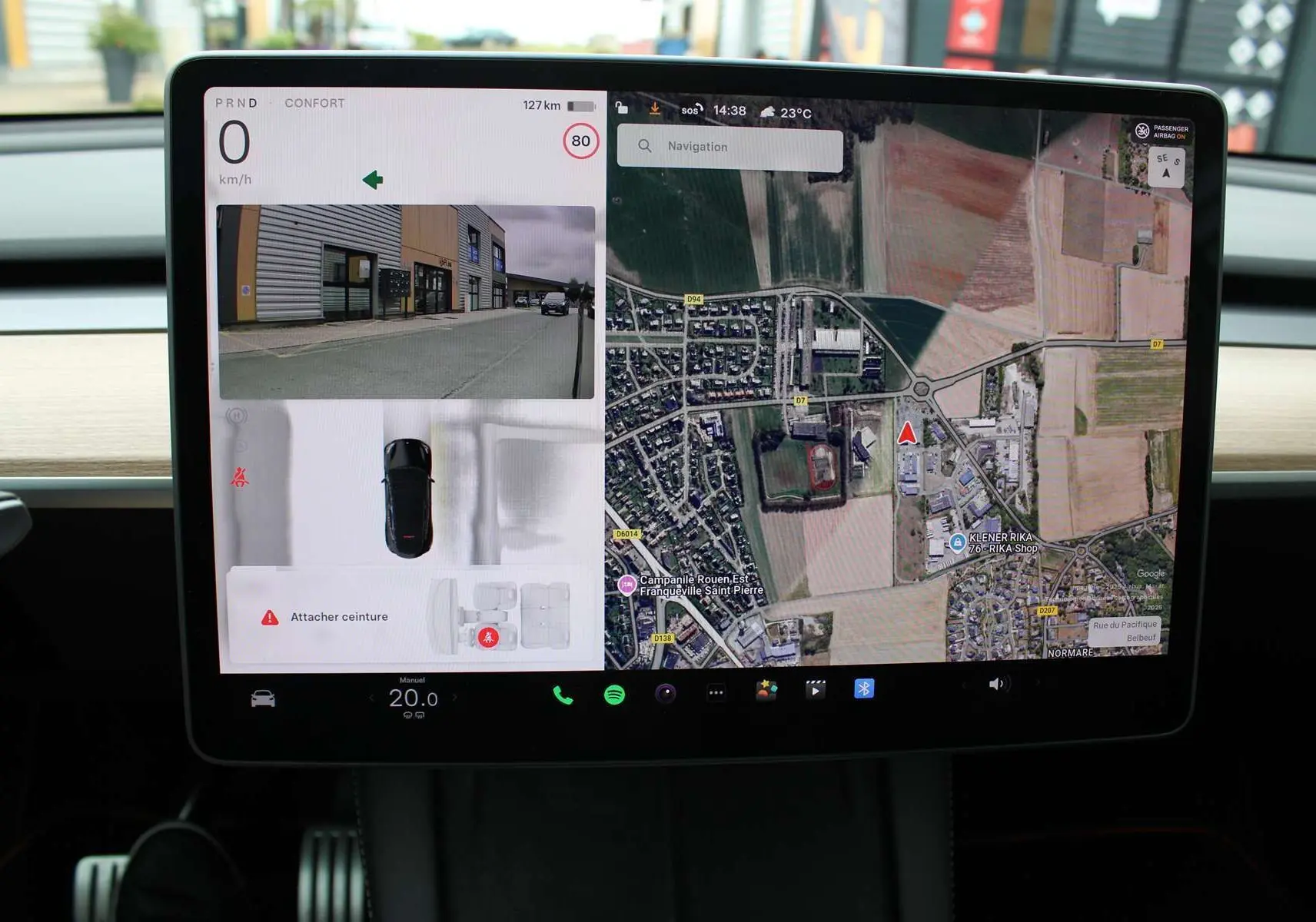 Écran tactile central de la Tesla Model Y Performance 2024 montrant navigation et caméra de recul en intérieur noir.