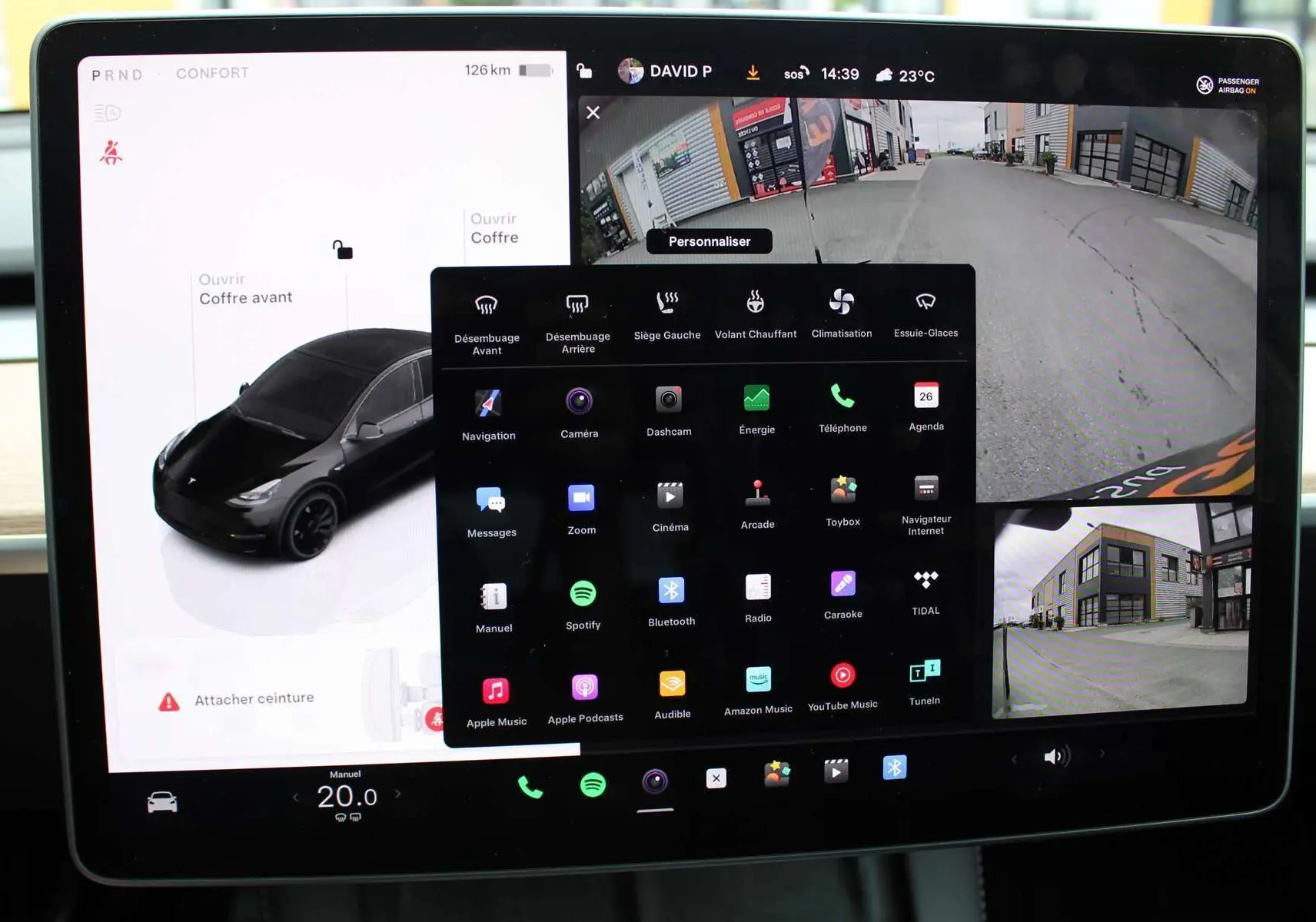 Écran tactile central de la Tesla Model Y noire 2024 montrant la caméra de recul et les options de contrôle intérieur.