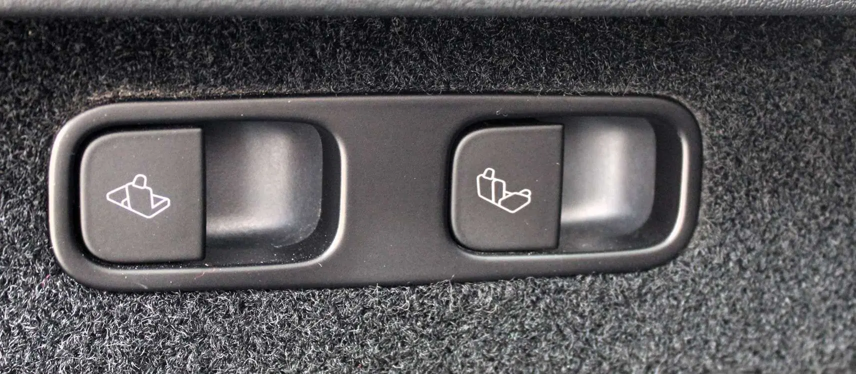 Gros plan sur les boutons de rabattement des sièges arrière du Tesla Model Y noir métal 2024, finition Performance.