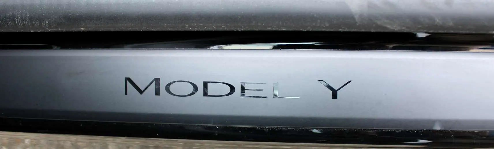 Gros plan sur la plaque noire métallisée avec l'inscription "MODEL Y" du SUV électrique Tesla 2024.