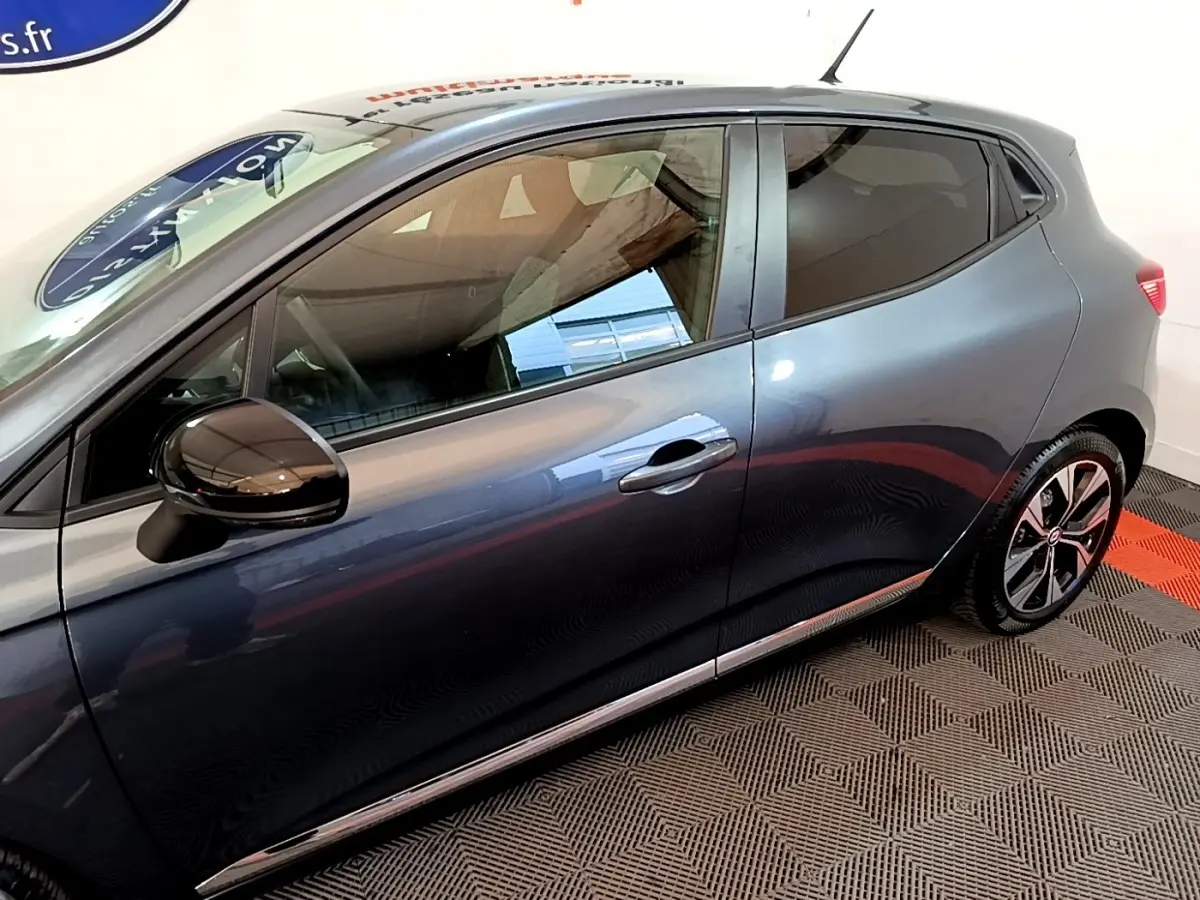 Vue latérale droite d'une Renault Clio gris foncé 2022 avec rétroviseur noir brillant et jantes alliage distinctives.