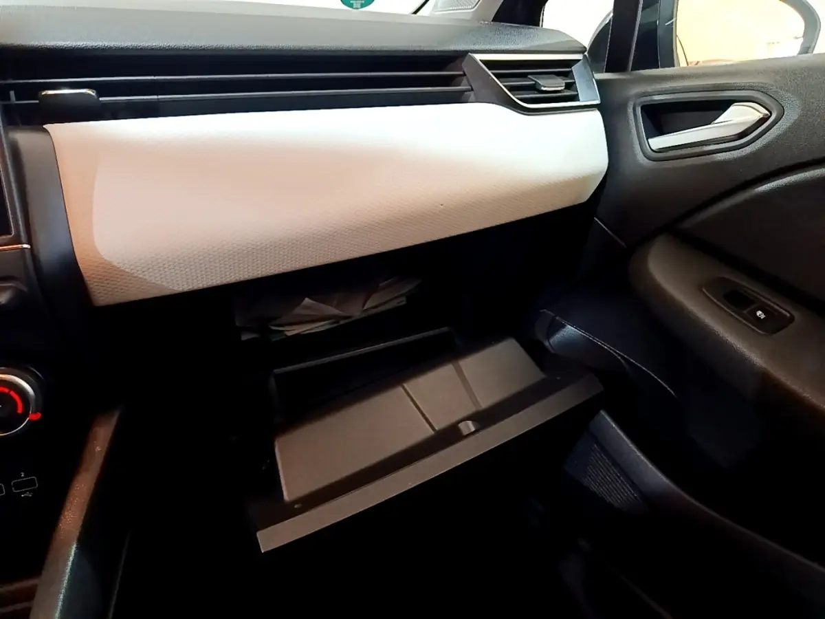 Intérieur de la Renault Clio Evolution SCe 65 2022, vue côté passager sur la boîte à gants ouverte et tableau de bord gris clair.