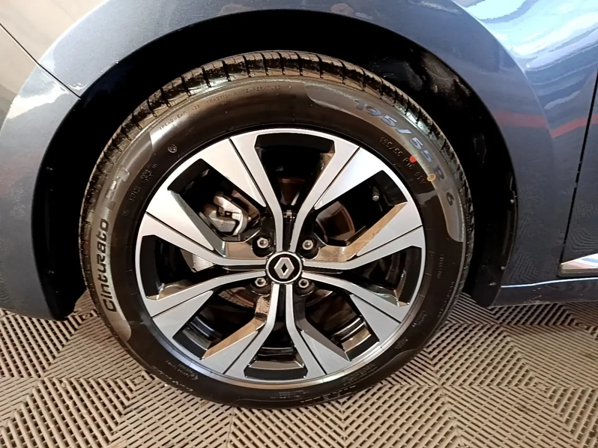 Gros plan sur la roue avant droite d'une Renault Clio gris foncé, avec jante alliage au design moderne et logo central Renault.