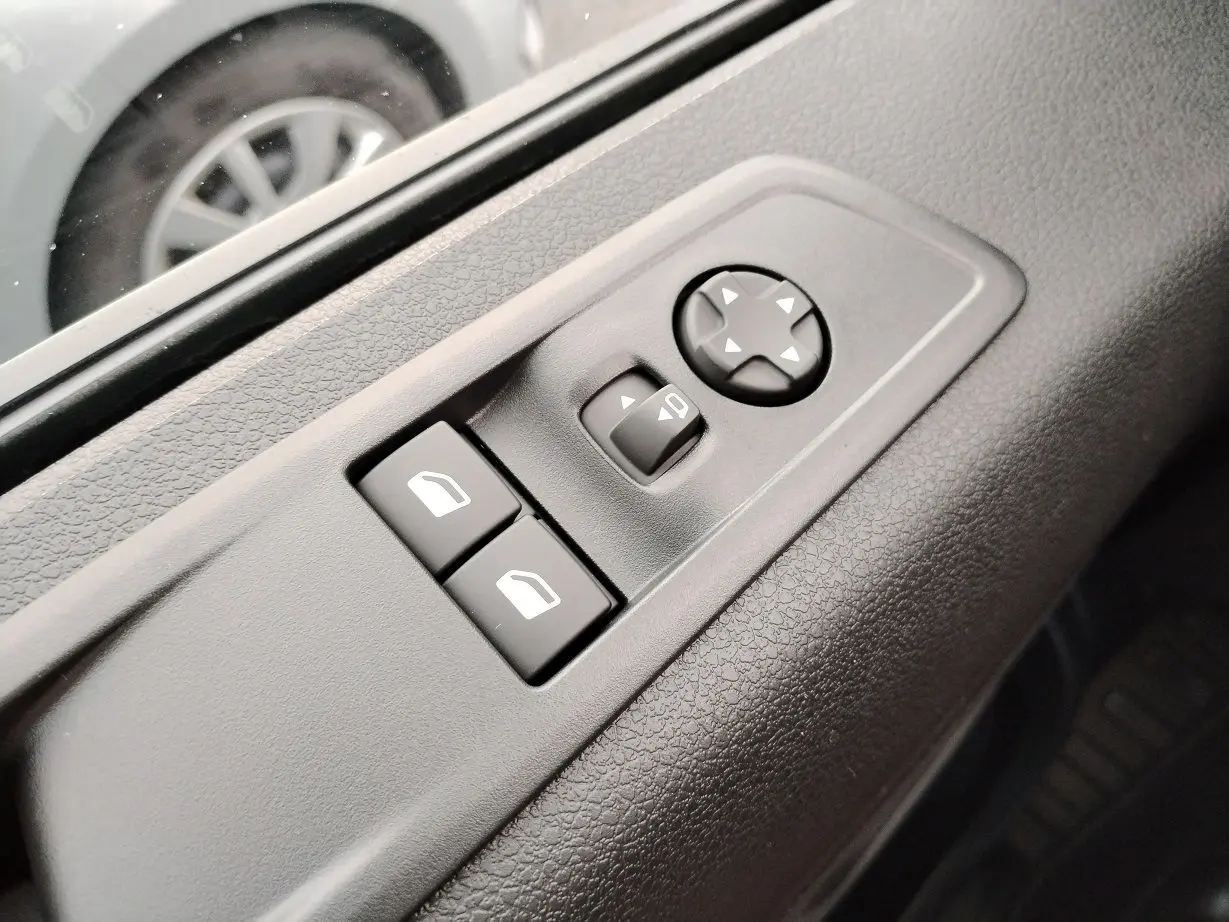 Gros plan sur les commandes de réglage des rétroviseurs et vitres côté conducteur du Fiat Ulysse noir Perla 2026.