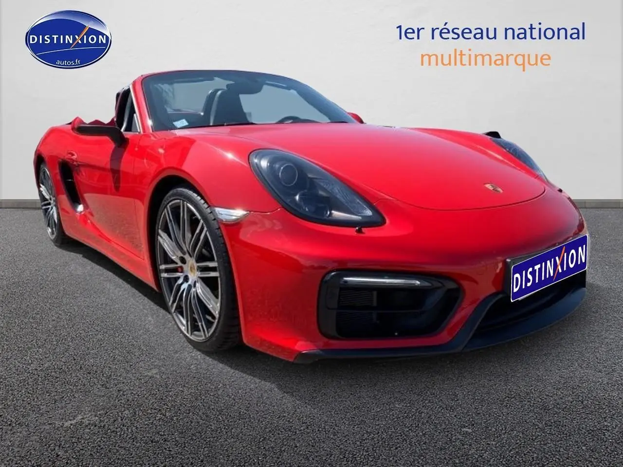 Vue 3/4 avant gauche d'une Porsche Boxster 981 rouge avec jantes alu et phares bi-xénon noirs.