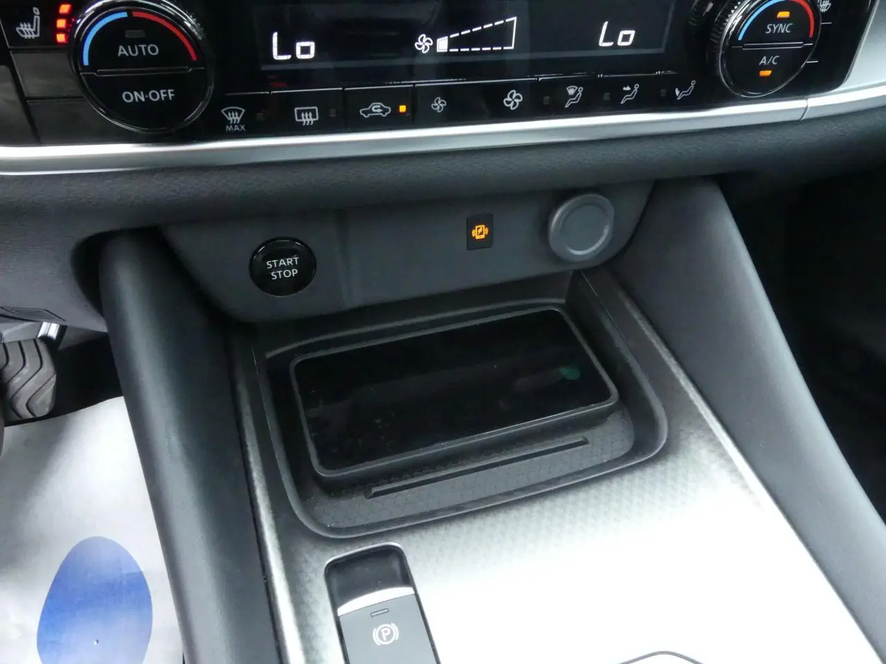 Vue rapprochée de la console centrale du Nissan Qashqai 2025 avec chargeur à induction et bouton Start/Stop noir.