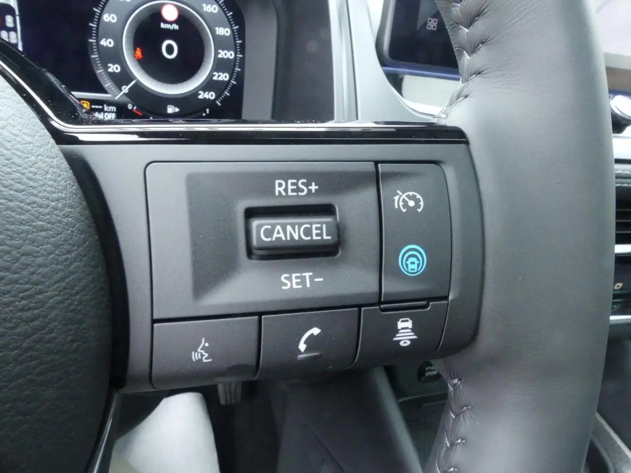 Gros plan sur les commandes au volant cuir du Nissan Qashqai 1.5 e-Power gris, affichage numérique en arrière-plan.
