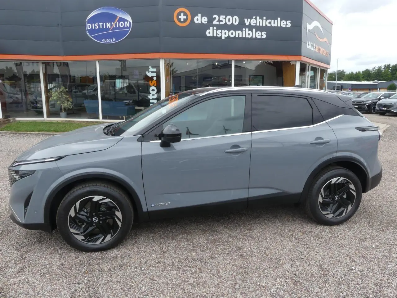Nissan Qashqai 1.5 e-Power gris métallisé vue de profil côté gauche avec toit noir et jantes alliage noires.